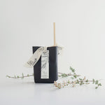 Load image into Gallery viewer, Black reed diffuser with a decorative ribbon on a white background