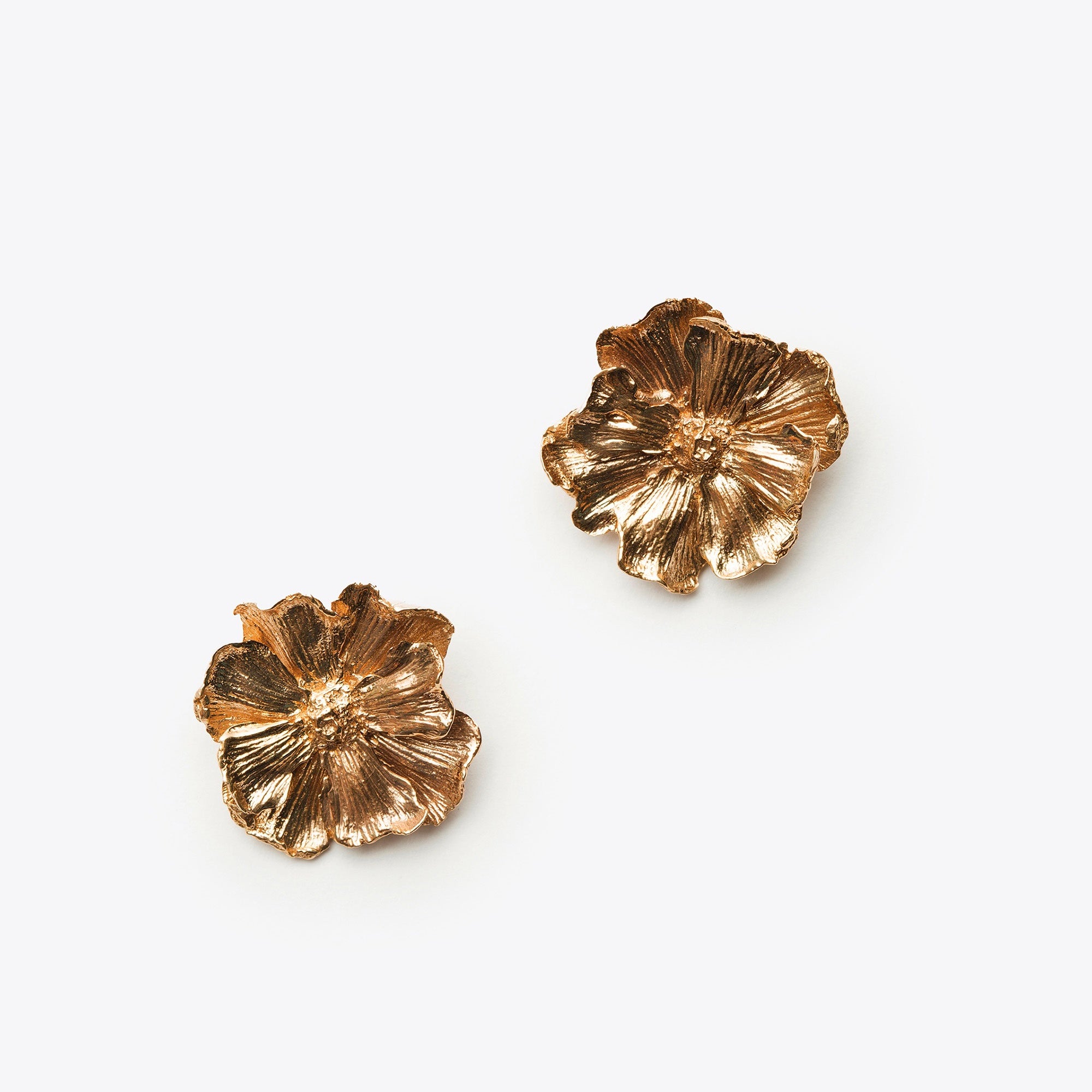 Pair of bronze floral earrings on a white background