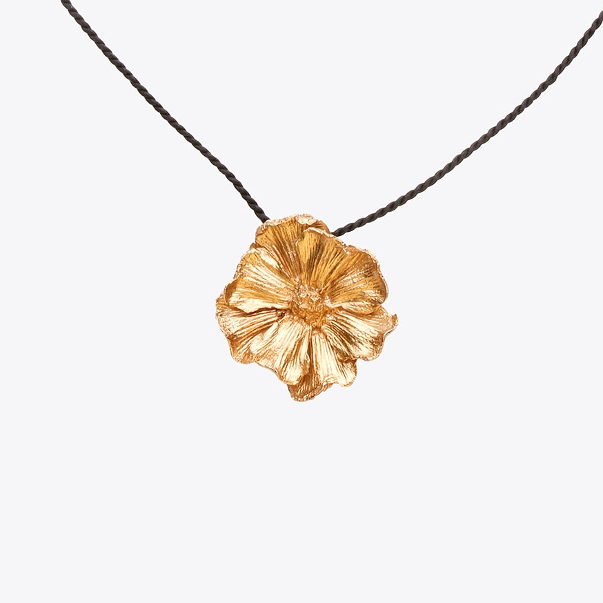 Bronze floral pendant on a black cord against a white background