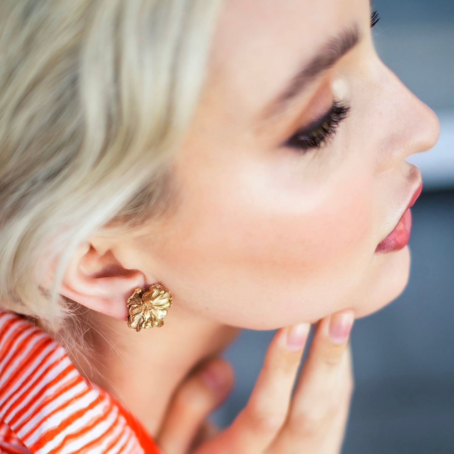 Close-up of a woman wearing bronze earrings with a blurred background