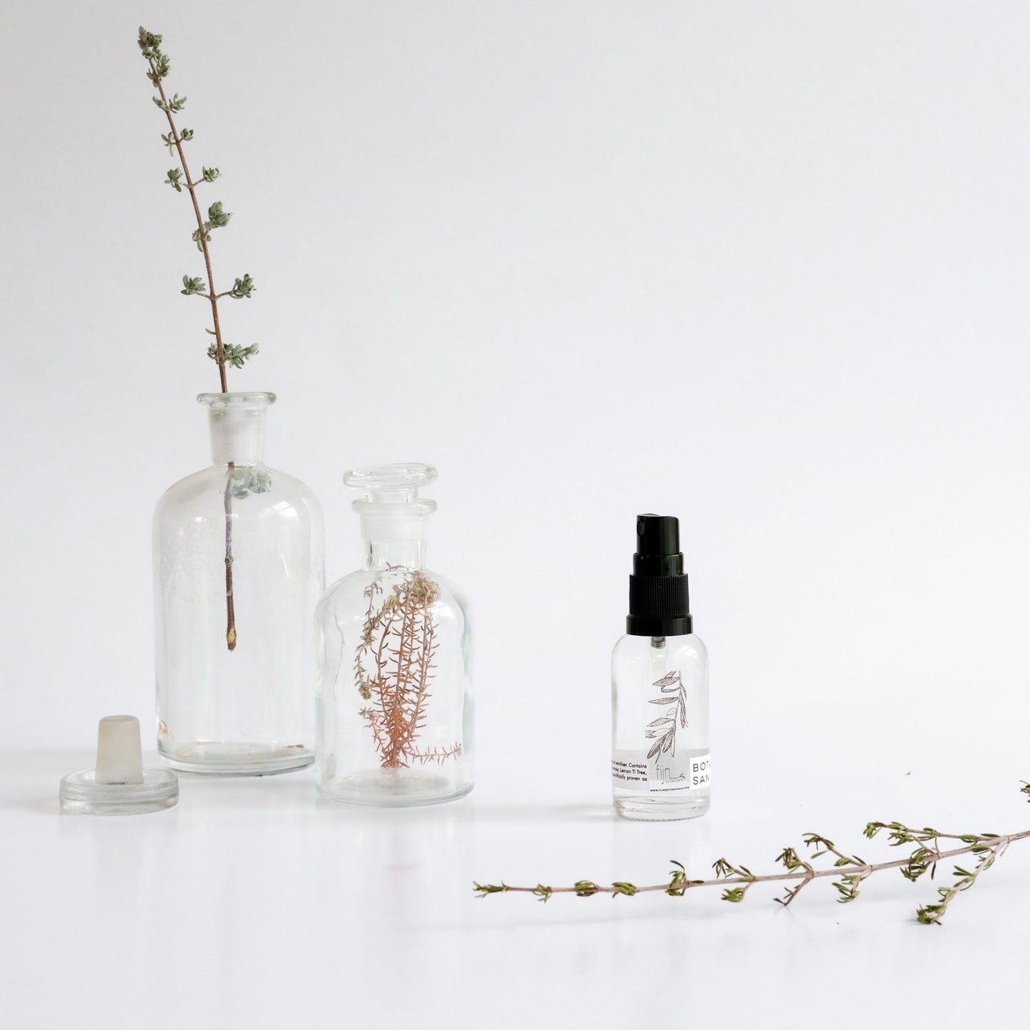 Clear glass bottles with natural elements on a white background