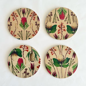 Four round coasters with floral patterns on a beige background