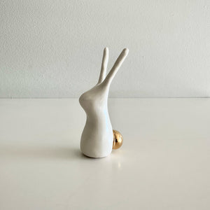 White ceramic rabbit figurine on a light gray surface with a white background