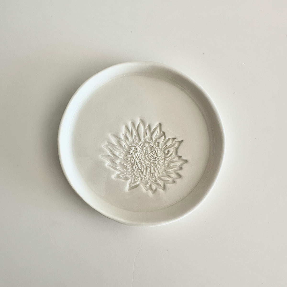 White ceramic plate with a protea design on a light gray background