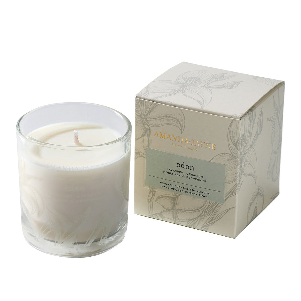 Glass candle with floral design and packaging on a white background