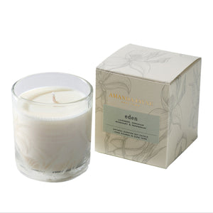 Glass candle with floral design and packaging on a white background