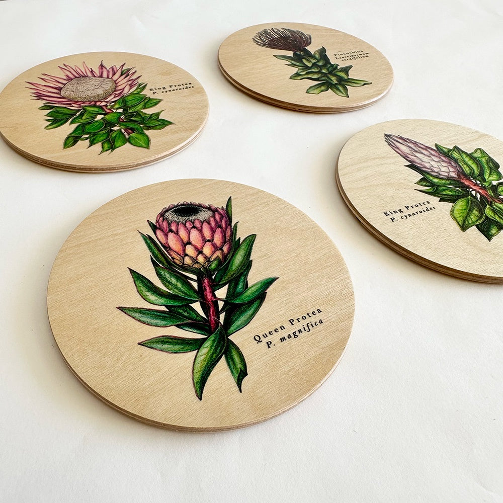 Set of four round wooden coasters with floral illustrations on a white background