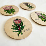 Load image into Gallery viewer, Set of four round wooden coasters with floral illustrations on a white background
