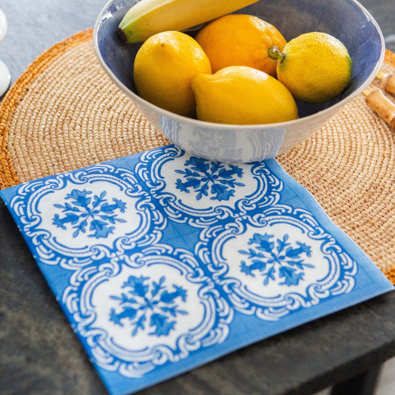 Bowl of lemons on a woven placemat with a blue decorative napkin.