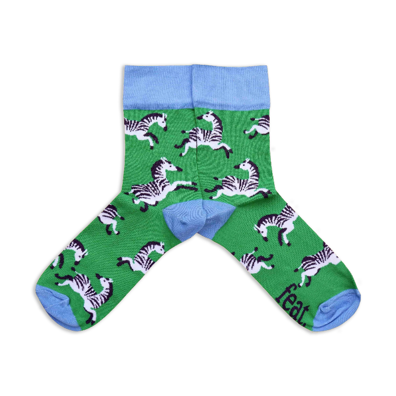 A pair of socks with a green background featuring zebra illustrations.