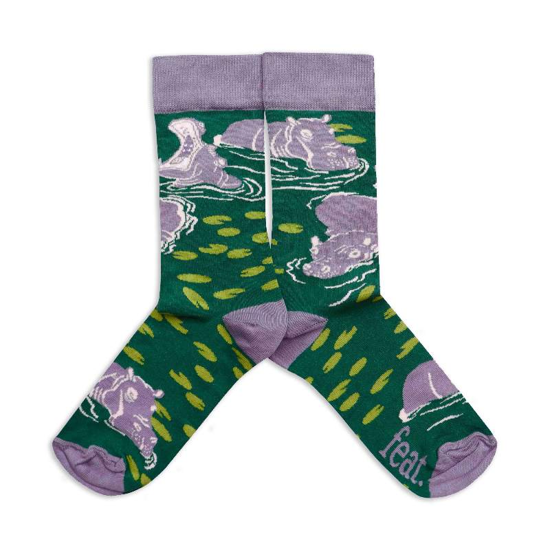 A pair of socks with a green background featuring hippo illustrations.