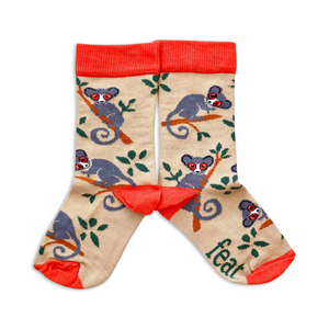 A pair of children's socks with a pattern of bush babies and foliage on a beige background, with red cuffs.
