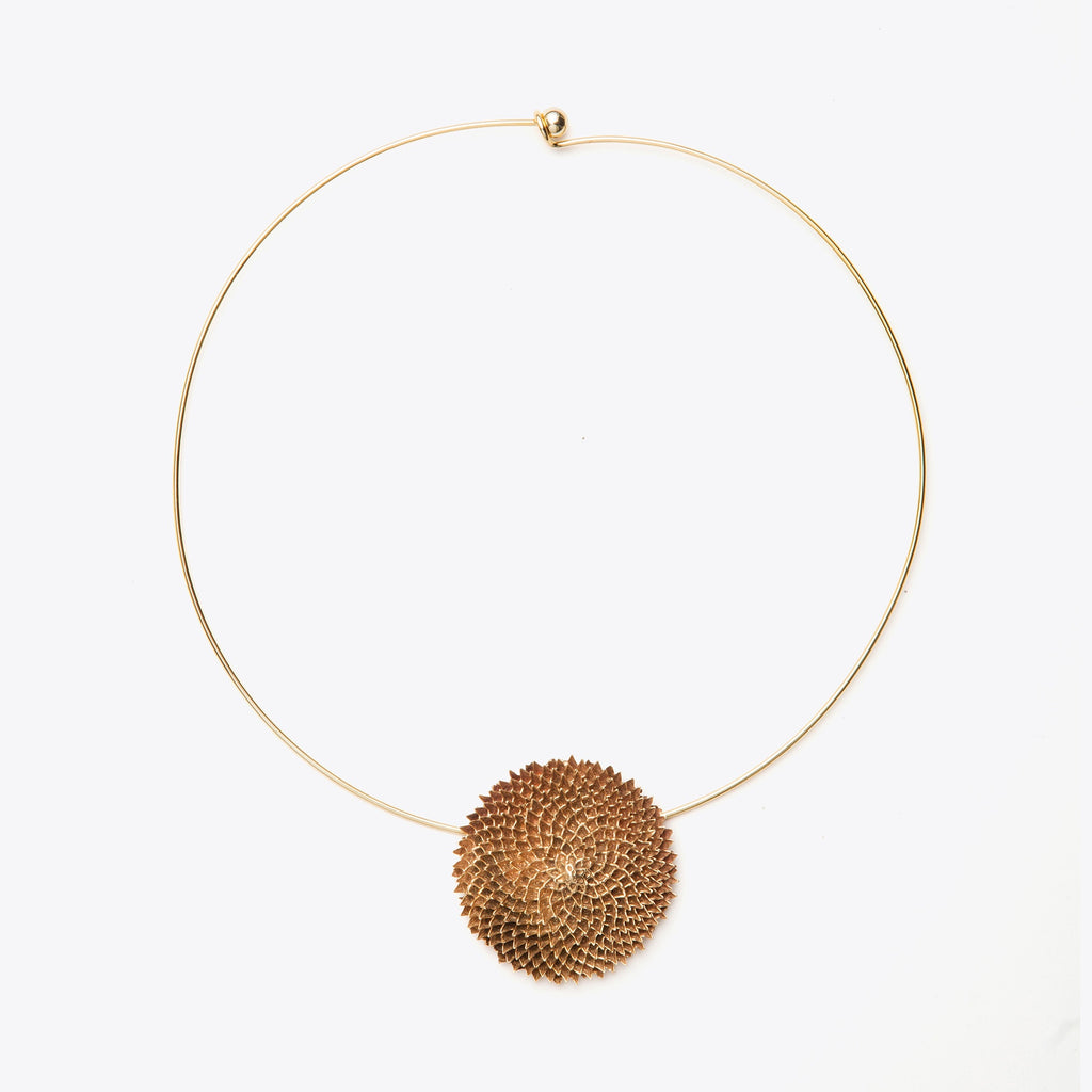 Bronze necklace with a textured round pendant on a white background