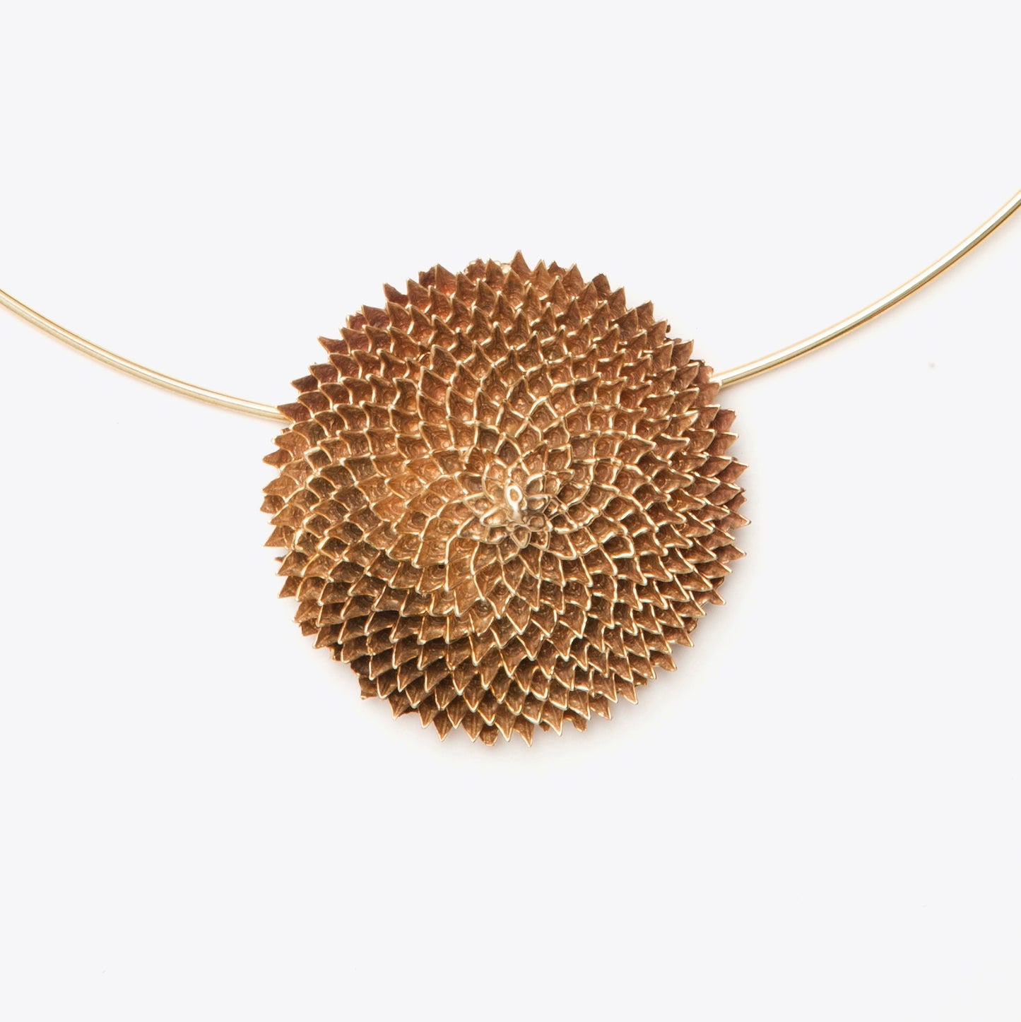 Bronze necklace with a textured, circular pendant on a white background