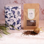 Load image into Gallery viewer, Tea packaging with a floral tin and a brown paper bag labeled LMC on a light surface.
