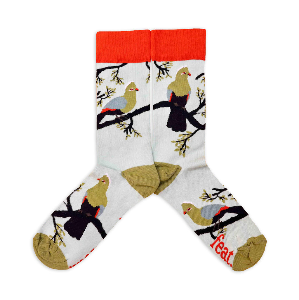 A pair of light blue cotton socks with a pattern of bright green and blue knysna loerie birds and the word 'feat' on the sole.