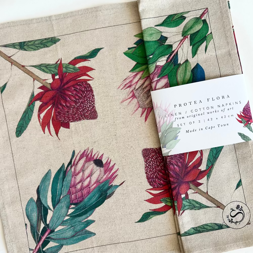 Protea-themed natural linen cotton napkins with packaging and label on a neutral background