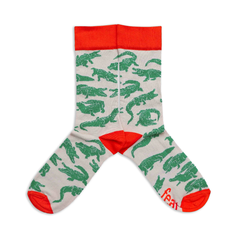 A pair of socks with a beige background featuring crocodile illustrations.