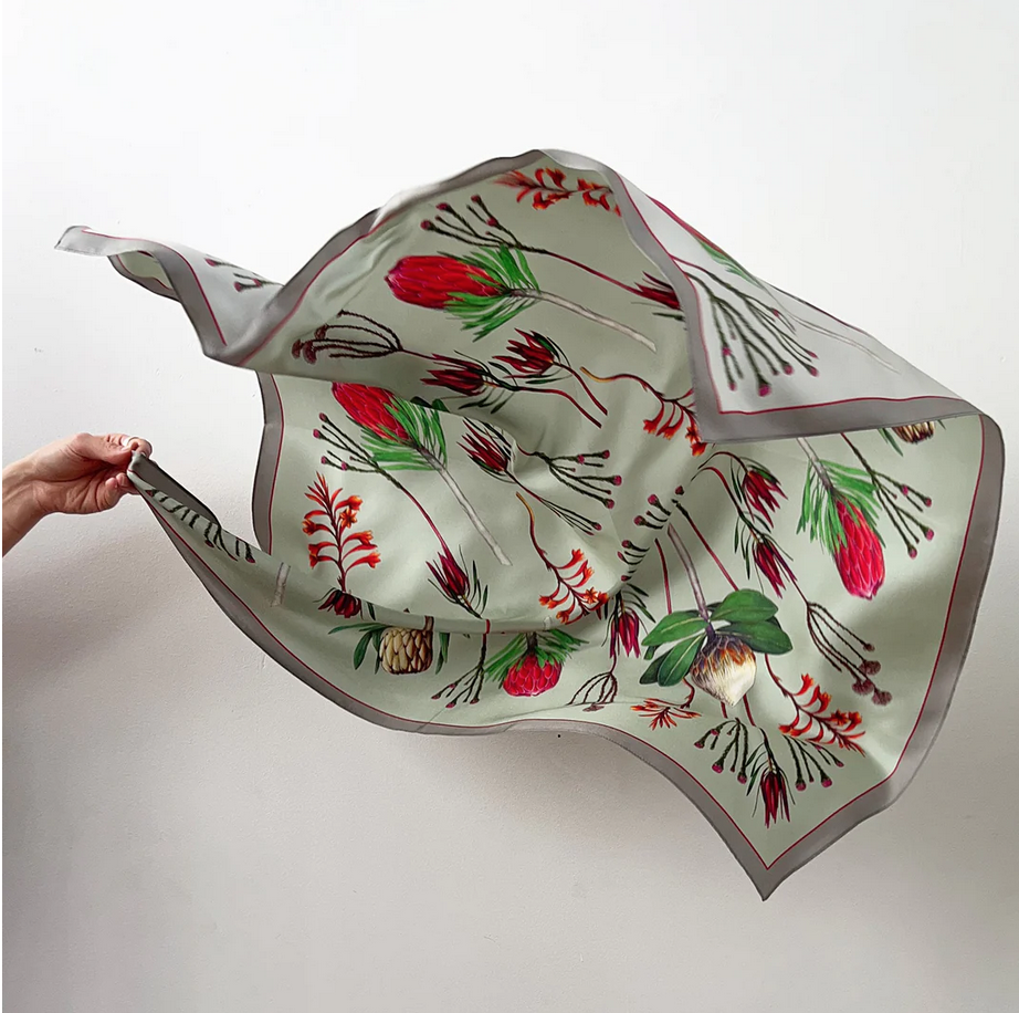 Floral patterned silk scarf being held up against a white background