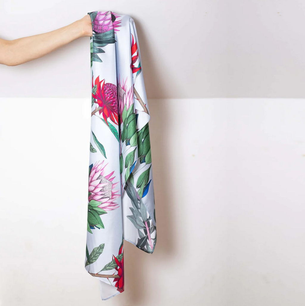 Botanical floral scarf held by a person against a white background