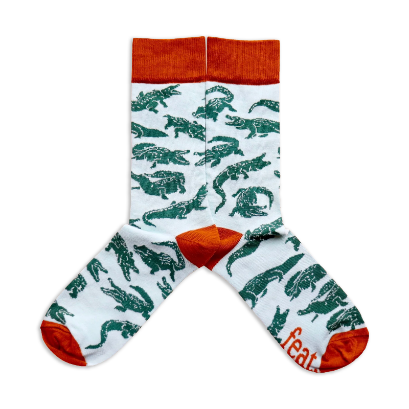 A pair of socks with a light blue background featuring crocodile illustrations.
