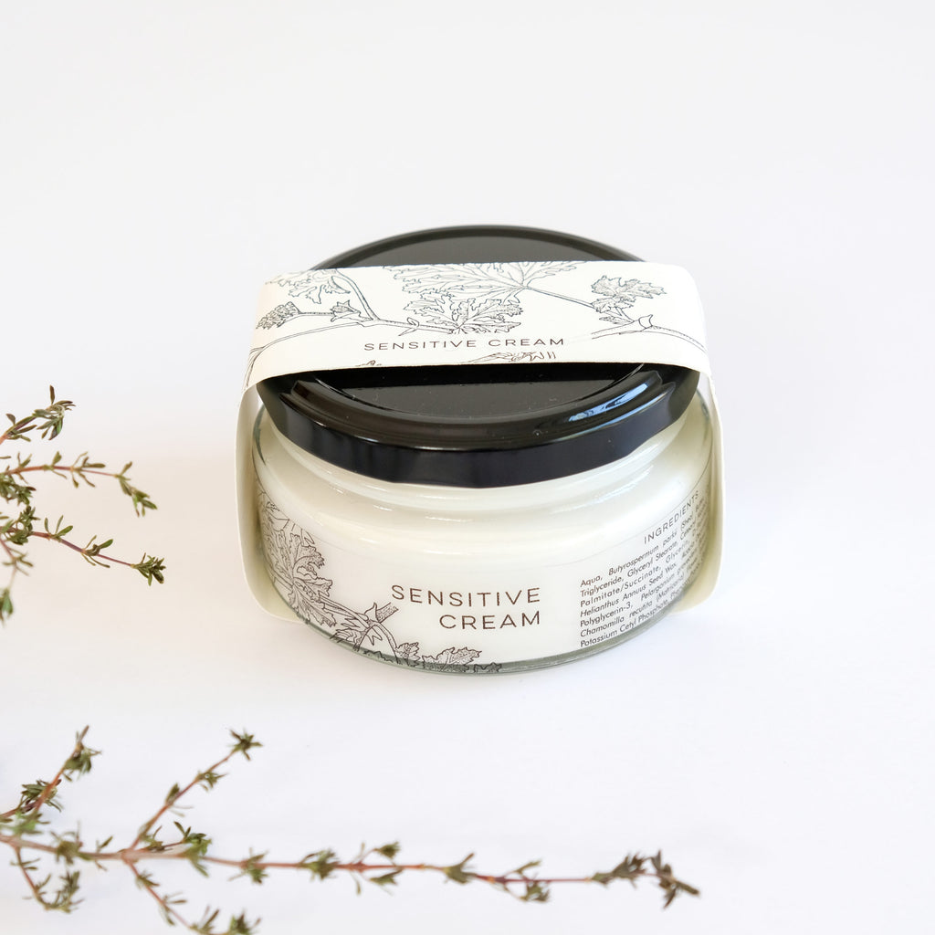 Jar of sensitive cream with decorative label on a white background