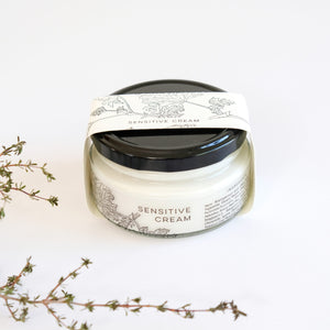 Jar of sensitive cream with decorative label on a white background