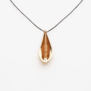Bronze teardrop shaped pendant on a black cord against a white background