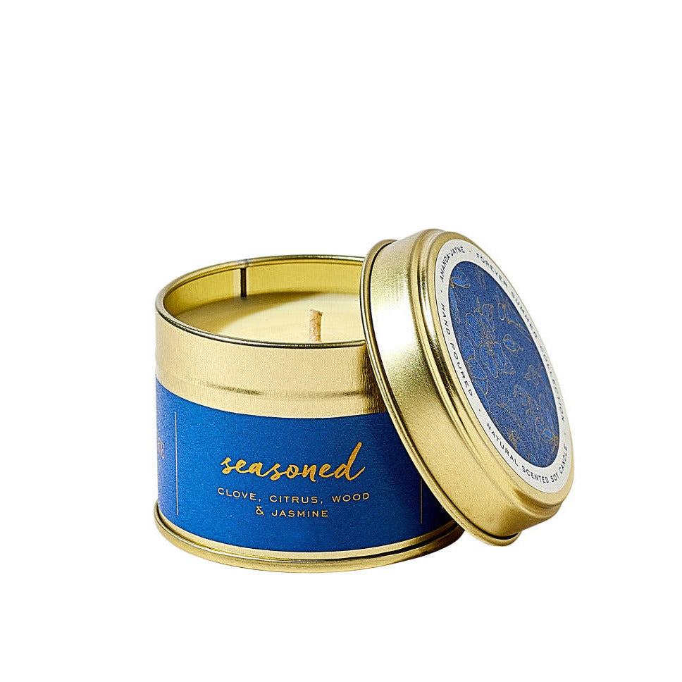 Candle in a gold tin with blue label on a white background