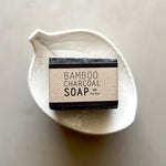Load image into Gallery viewer, Bar of bamboo charcoal soap in a white dish on a neutral background
