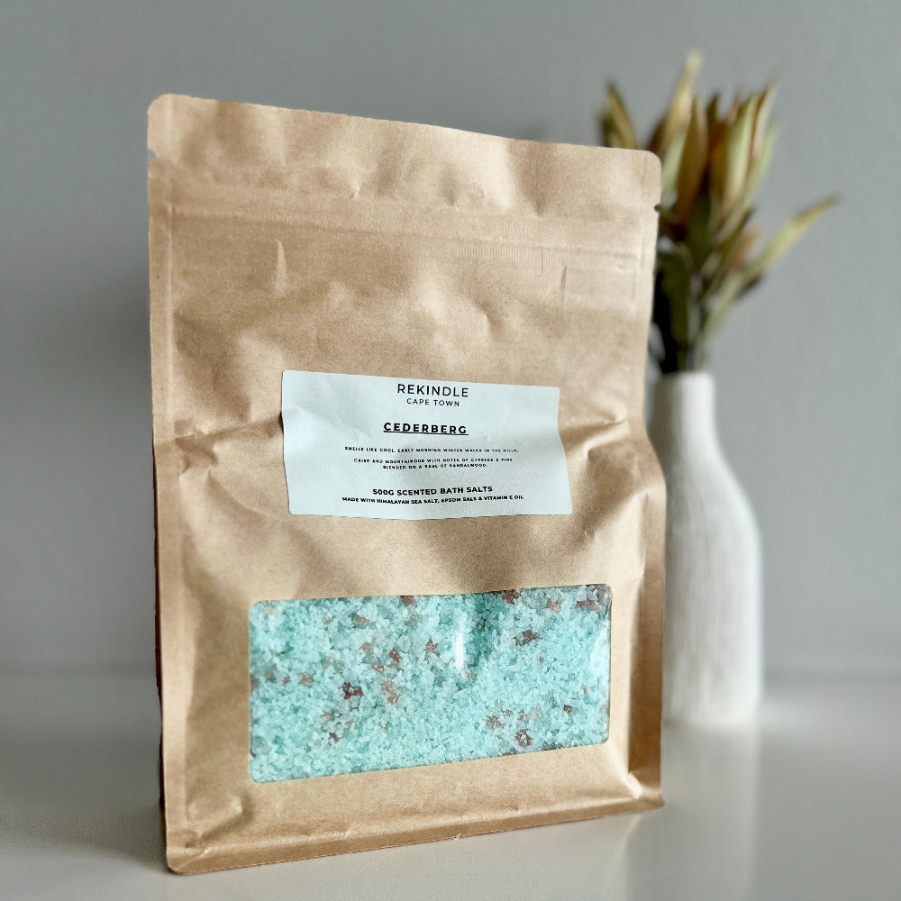 Brown paper bag with a label and visible blue bath salts on a gray background