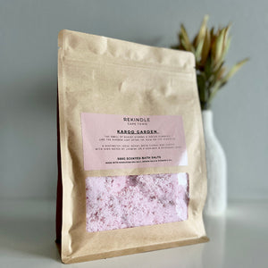 Kraft paper packaging of bath salts with a pink label on a neutral background