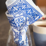 Load image into Gallery viewer, Blue and white patterned napkin in a glass with a blurred cup in the background
