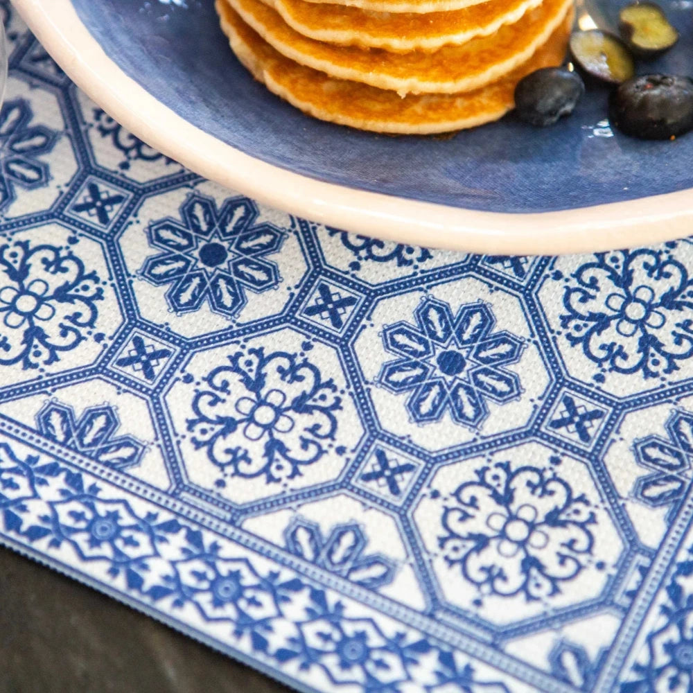 Blue and white patterned placemat with a plate of pancakes and fruit on a wooden surface