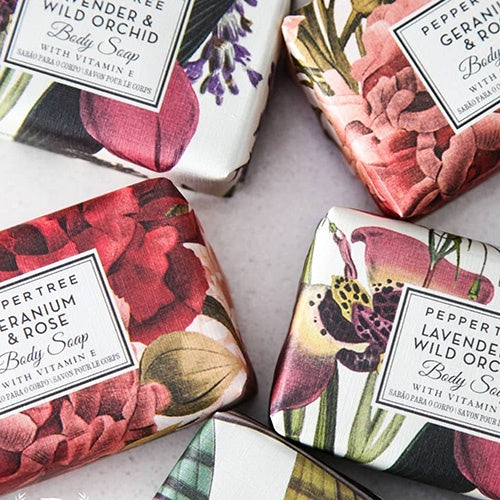 Four floral-themed body soaps on a light surface