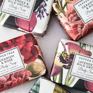 Four floral-themed body soaps on a light surface