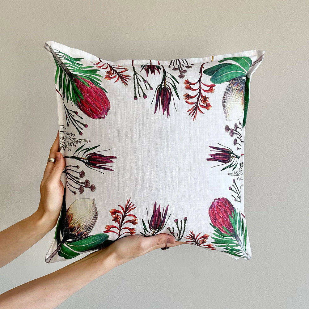 Fynbos floral patterned pillow held by a hand against a neutral background