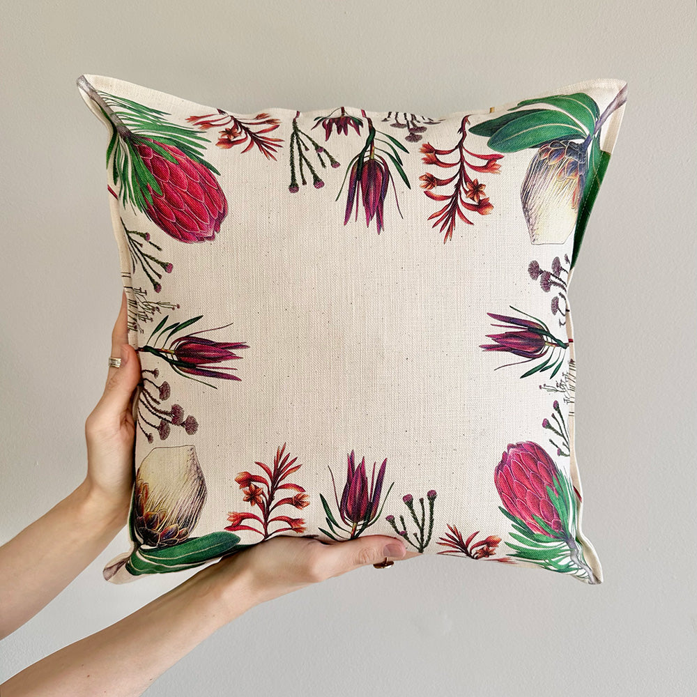 Fynbos floral patterned pillow held by a hand against a neutral background