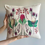 Load image into Gallery viewer, Decorative pillow with fynbos floral design held by a hand against a plain background
