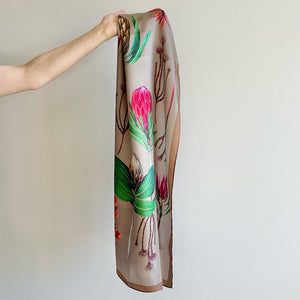 Silk scarf with floral design held by a hand against a plain background