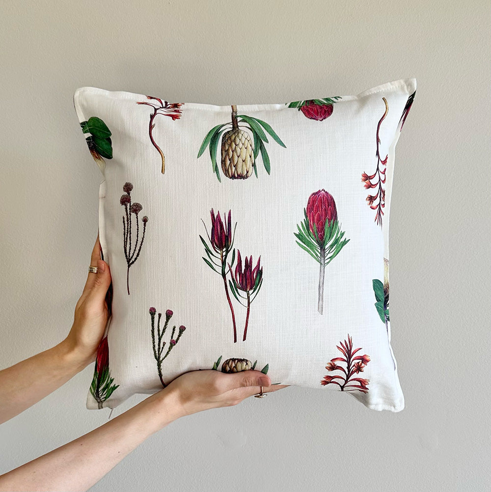 Fynbos floral patterned pillow held by a person against a neutral background