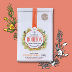 Load image into Gallery viewer, Sunbird Rooibos tea tin on a peach background with tea leaves and flowers.
