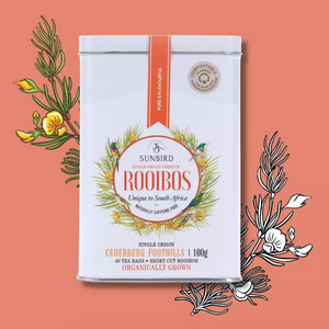 Sunbird Rooibos tea tin on a peach background with tea leaves and flowers.
