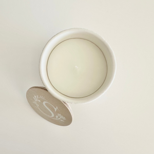 Round white candle in a white container on a light gray background