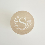 Load image into Gallery viewer, Round wooden lid with a white monogram &#39;S&#39; design on a light gray background
