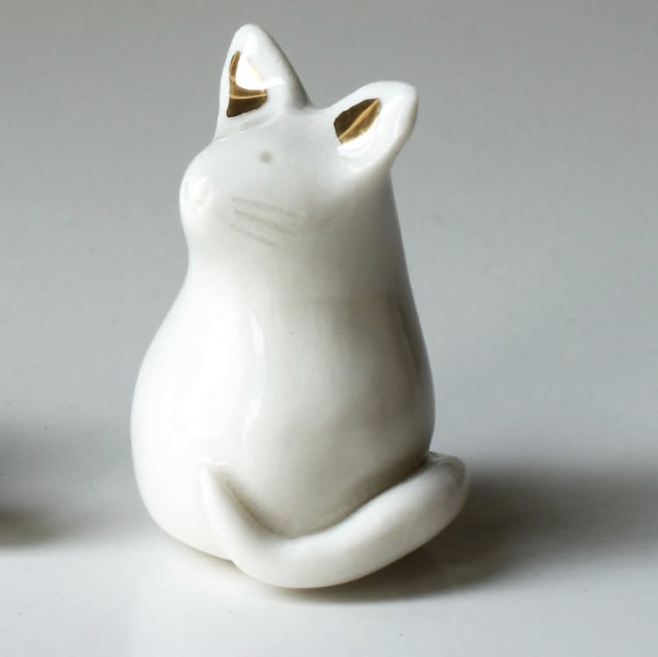 White ceramic cat figurine with gold accents on a gray background
