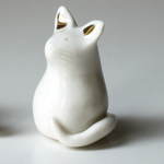 Load image into Gallery viewer, White ceramic cat figurine with gold accents on a gray background
