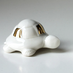 Load image into Gallery viewer, White ceramic turtle figurine with gold accents on a gray background
