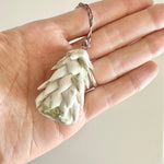 Load image into Gallery viewer, Hand holding a white porcelain ornament on a plain background
