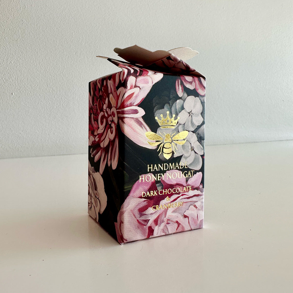 Floral packaging box for honey nougat with a bee design on a white background